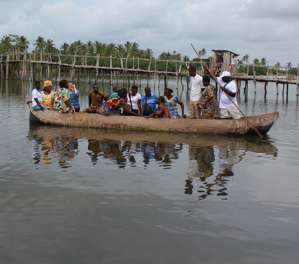 A canoe filled with people poles out from shore