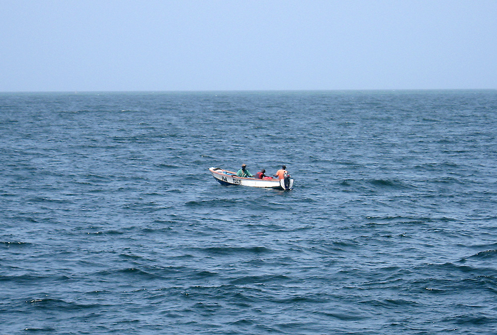 3 fishermen in a small boat in the distance